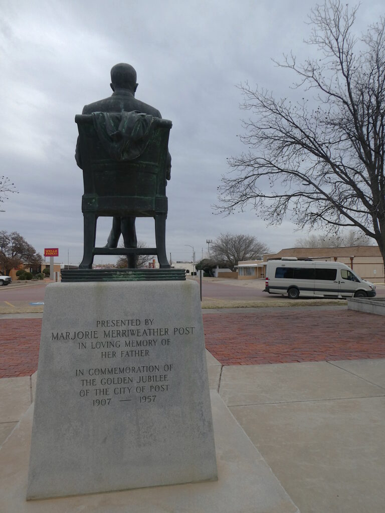 Statue of C. W. Post by his Daughter with MooVan and the town of Post in the background.